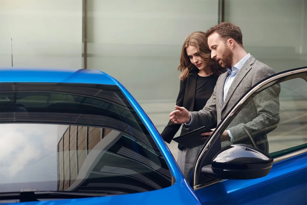 mannelijke autoverkoper verkoopt blauwe auto aan vrouwlijke klant