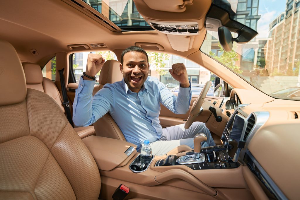 happy motorist sitting at steering wheel of his car