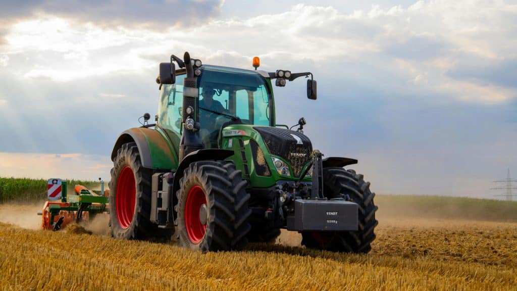 Fendt tractor ploegend over akker bij zonsondergang