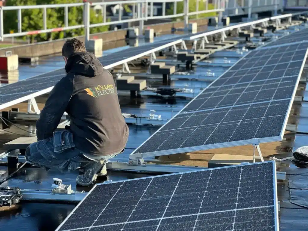 Monteur van Holland Electric installeert zonnepanelen op bedrijfsdak.